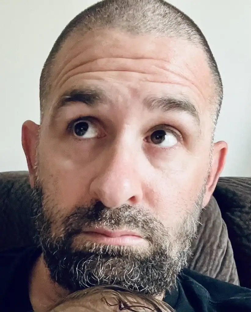 Headshot of a bearded man with a shaved head looking slightly upward indoors. Chris Obrien