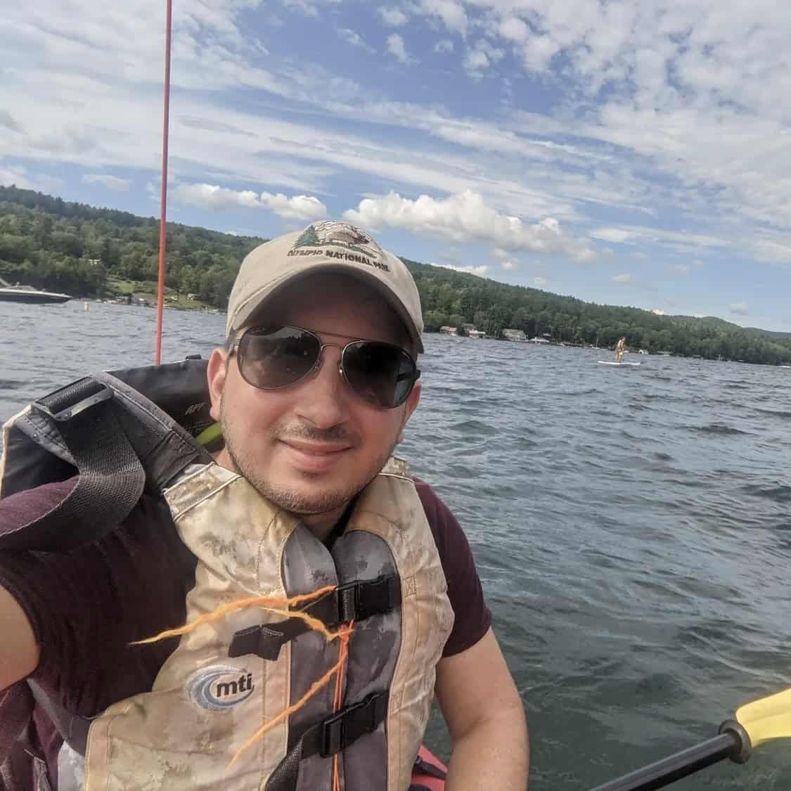 A man in a life vest on a lake poses.