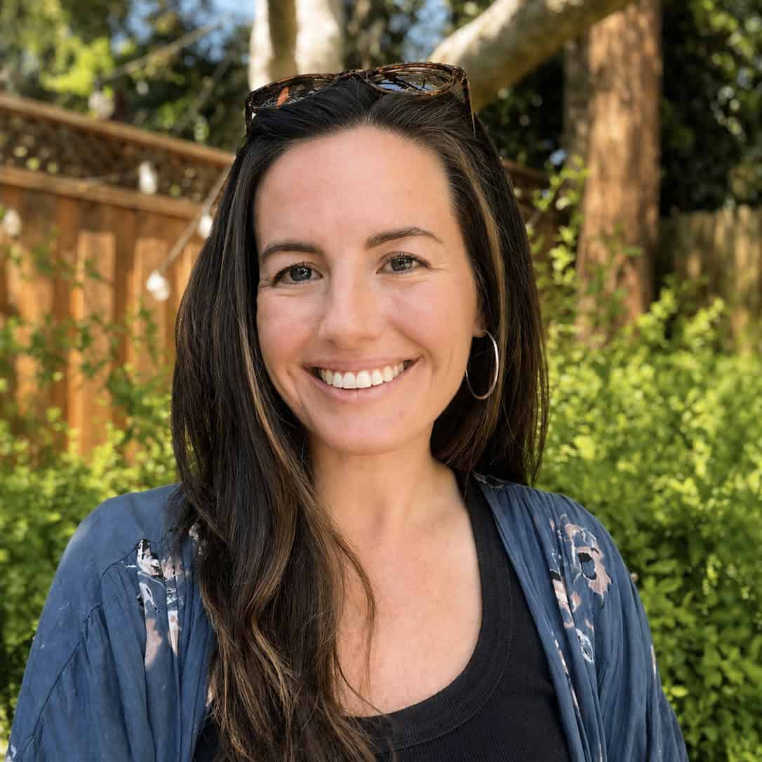 A woman with brown hair smiles outside