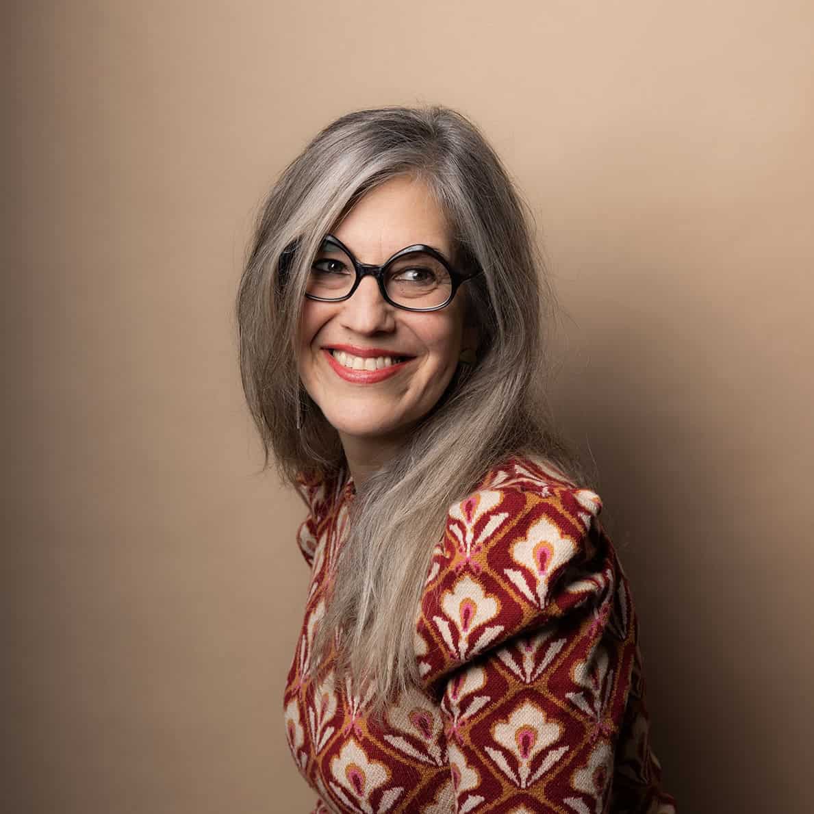 A woman with glasses smiles.