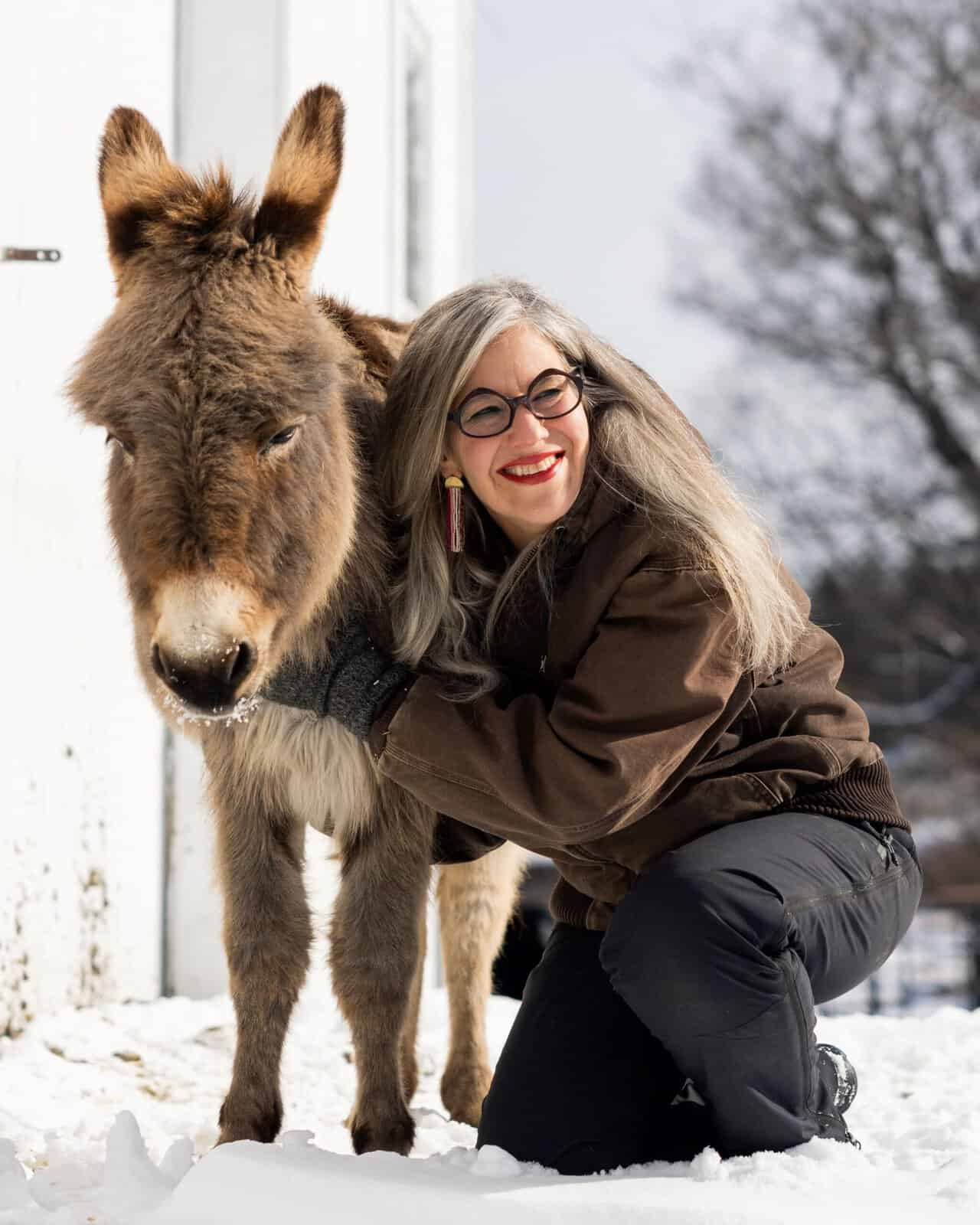 a woman smiles with a donkey
